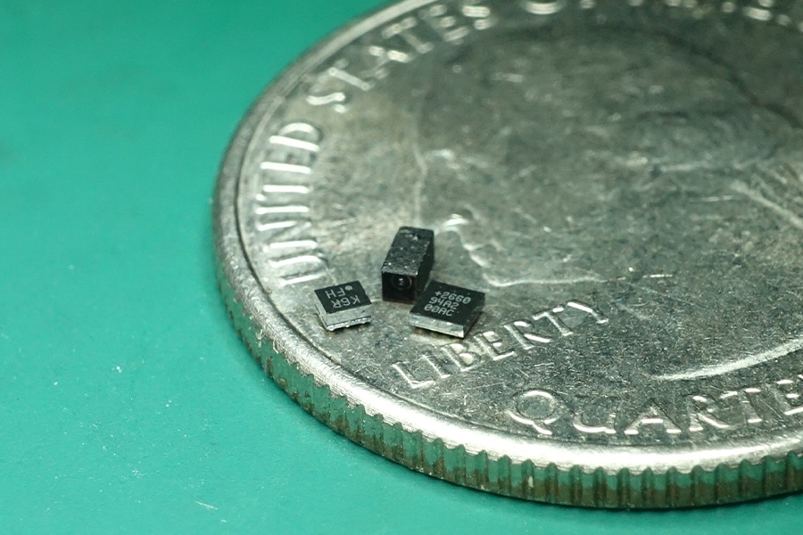 An accelerometer that detects airspeed and a tiny optic flow camera placed on a quarter to show their small scale.