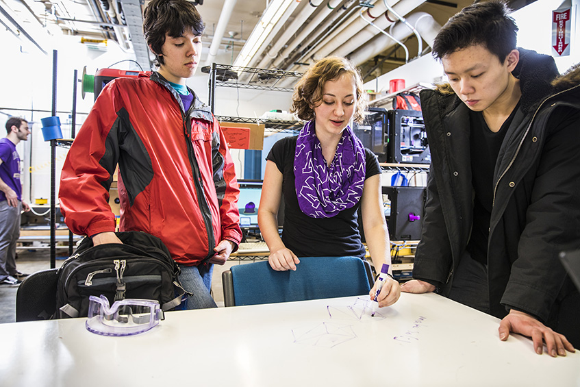 image of three students diagramming a 3d model on a table