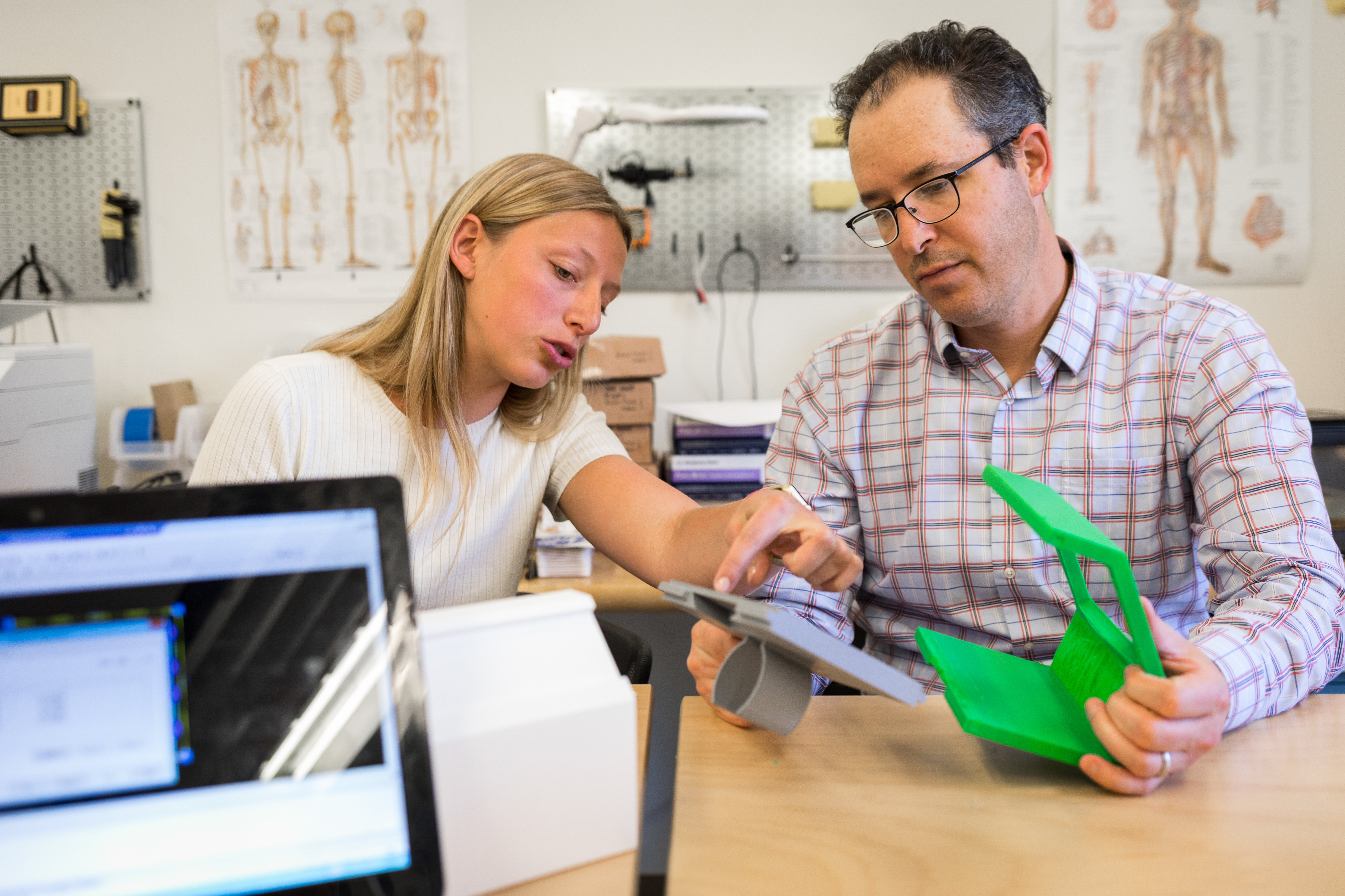 A faculty reviews a student's medical device prototype