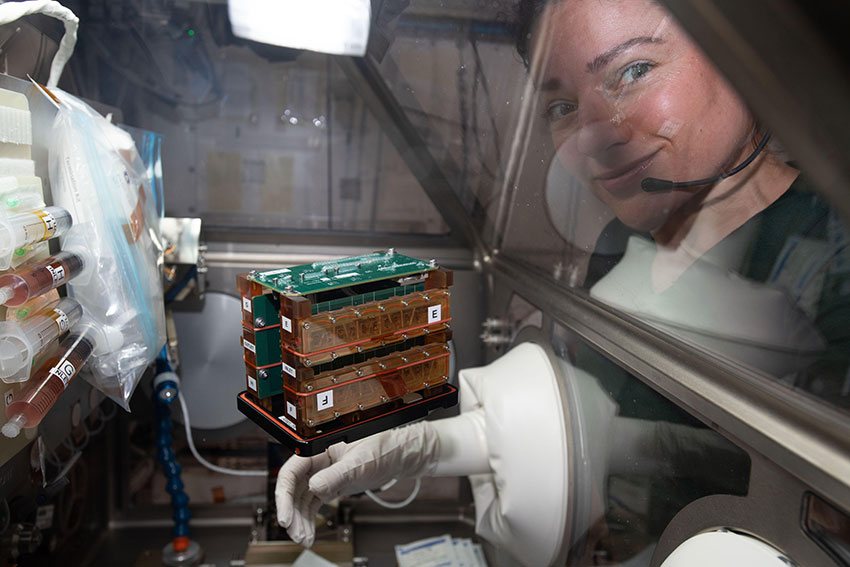 An astronaut next to a device floating in space