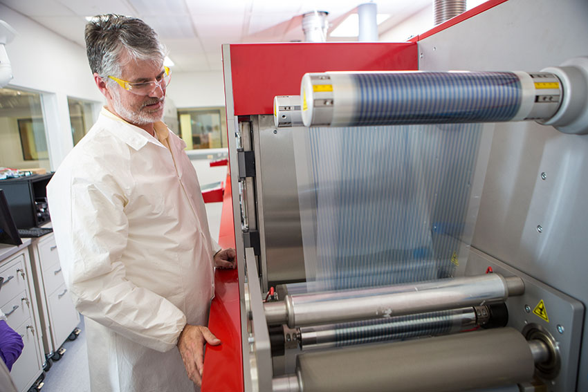 Devin MacKenzie standing next to lab equipment