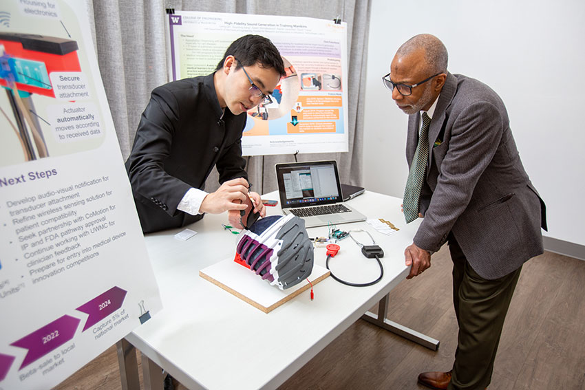 Student demonstrating a medical device to a visitor at an exhibition booth
