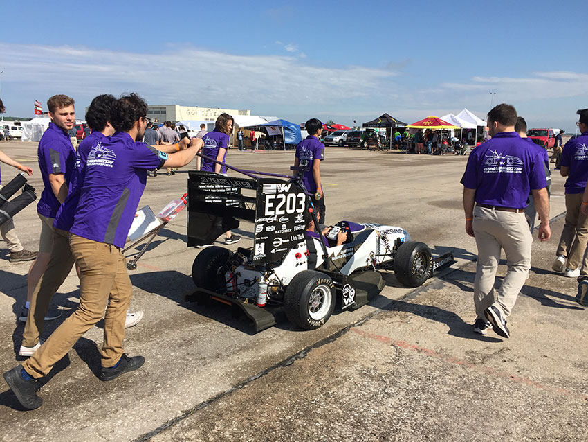 Students pushing a race car