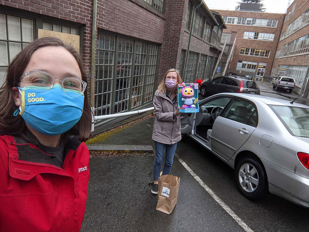 Two students standing in a park lot, one of whom is holding up a toy