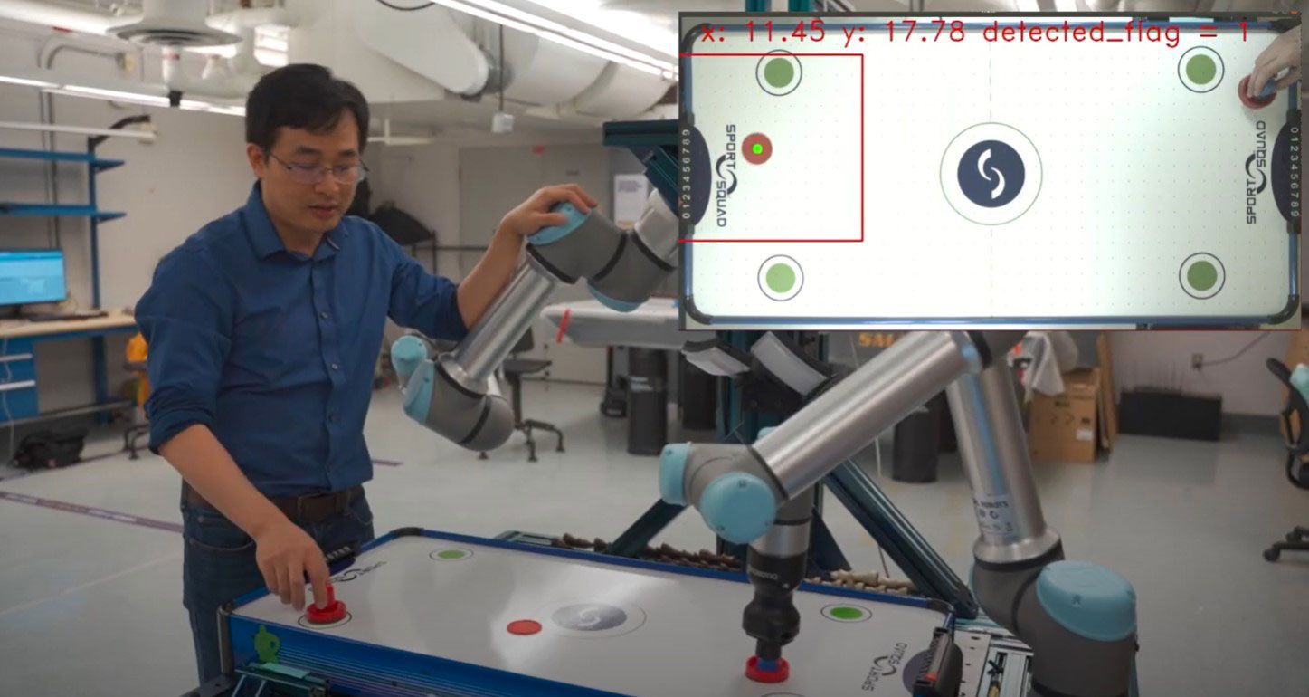 Chen interacting with air hockey pieces near the robot