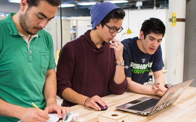 Students standing in front of a laptop computer