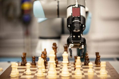 A robot arm hovering above a chessboard