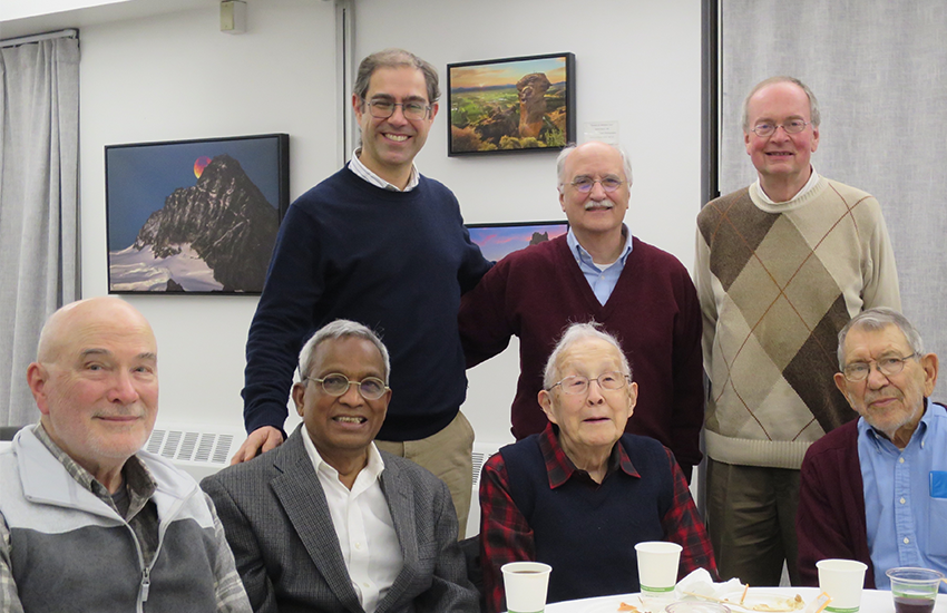Albert Kobayashi sits at a table surrounded by six current or former mechanical engineering professors.