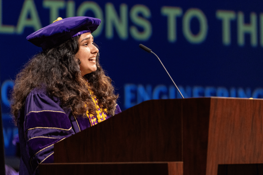Niharika Karnik speaks into a microphone behind a podium.