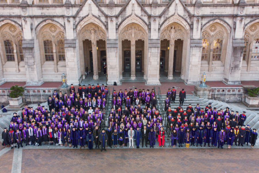 Aerial shot of faculty and students wearing robes standing in front of a building