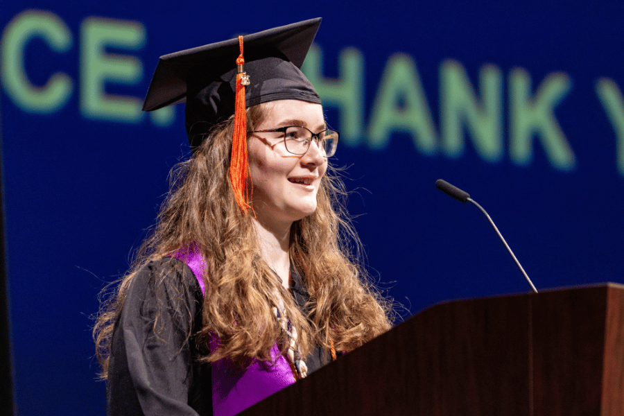 Ella Ramos-O’Neill speaks into a microphone behind a podium.