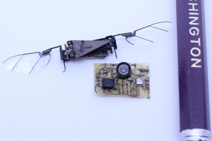 The sensor suite on a table next to an insect robot with wings and part of a pencil for scale.