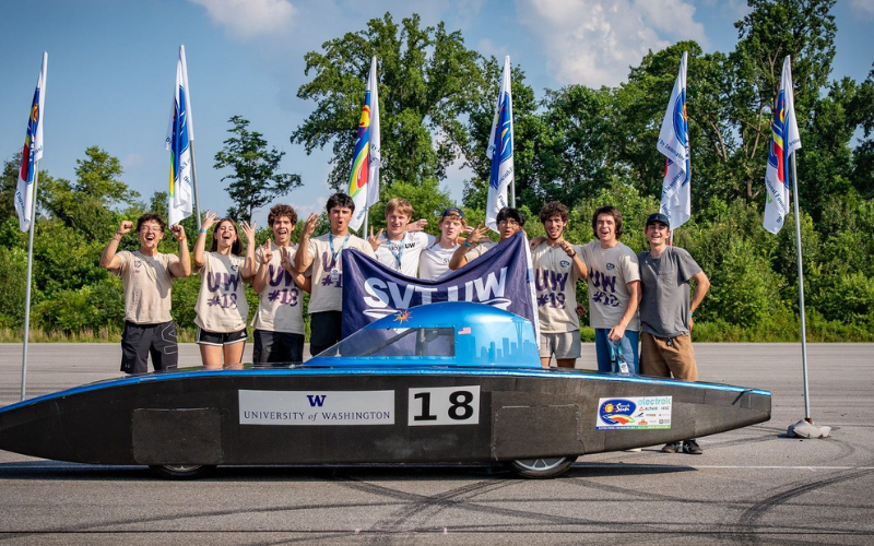 Students on the UW Solar Vehicle Team stand around their vehicle at the competition.