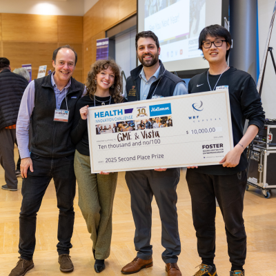 Four people stand smiling and holding a large fake check for $10,000.