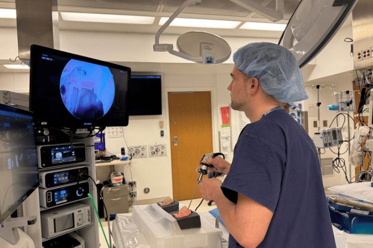 In a hospital setting, Graham Harris holds a probe in a sinus model while checking the endoscopic video on a screen.