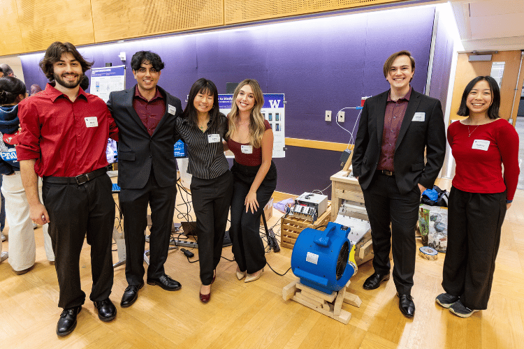 Six students stand by their poster and their wind tunnel prototype, which includes a fan, at the capstone expo.