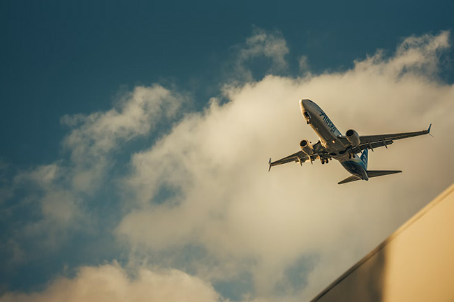 An airplane viewed from below, flying against a blue sky
