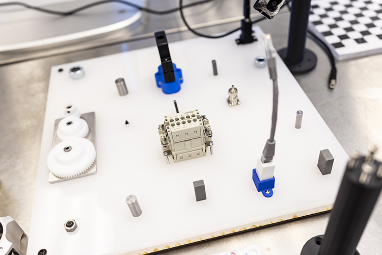 A board of different manufacturing parts, such as cylinders, screws and wires.