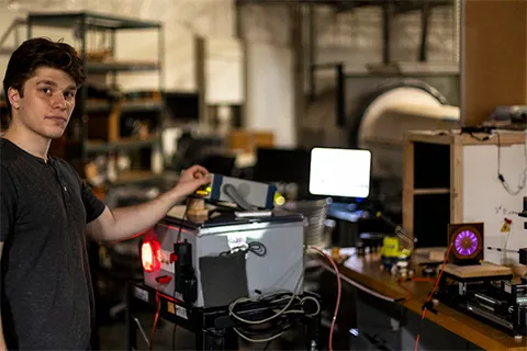 A person in a lab adjusting a device and looking at the camera