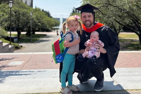 Tyler LeRoy at the UW for his graduation in June 2025 with his daughters, age 4 years and 2 months.