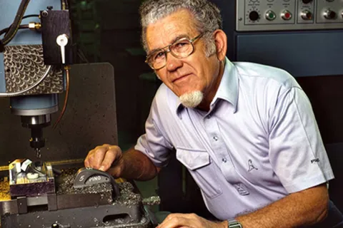 Person poses for a picture using a machine for manufacturing golf clubs