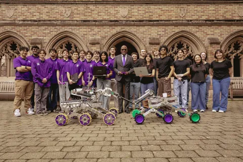 Two robotics teams posing for the camera with President Jones 