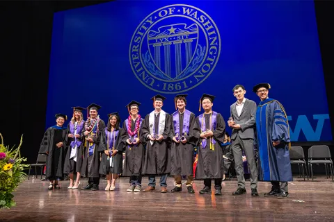 ME faculty standing with a group of 2026 graduates holding their student awards onstage