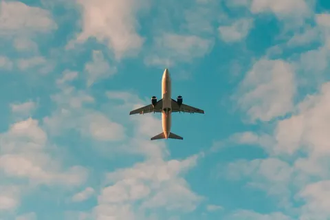 An airplane viewed from below, flying against a blue sky