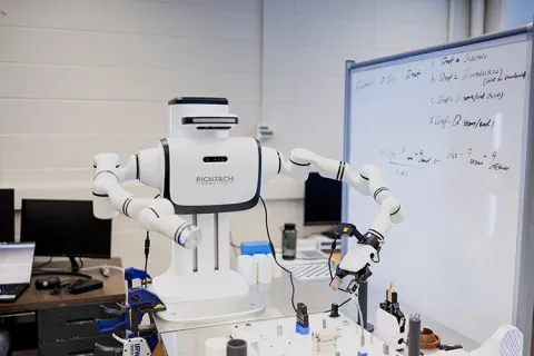 robot standing next to a whiteboard