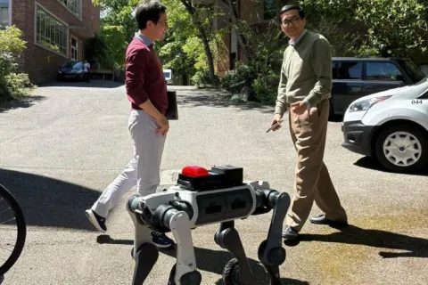 Xu Chen and Jihui Yang walk a robot dog on the UW campus.