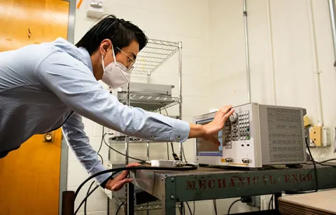 A researcher pressing buttons on an electronic device in a lab
