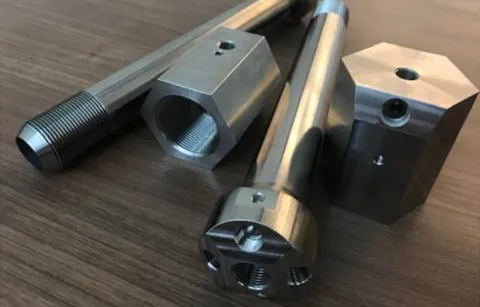 Metal objects on a table. There are two tubes and also two other hexagonal shapes.