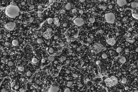 Gray blobs of liquid metal are scattered within a black background