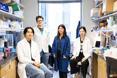 Four people in lab coats in a laboratory setting