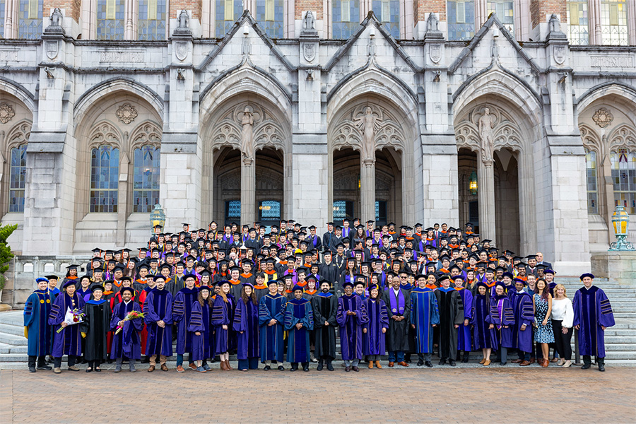 Students and faculty stand in front of the Suzzallo and Allen Libraries building at the 2023 graduation celebration.
