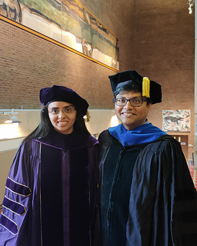 Ekta Samani and Ashis Banerjee are smiling and wearing graduation robes.