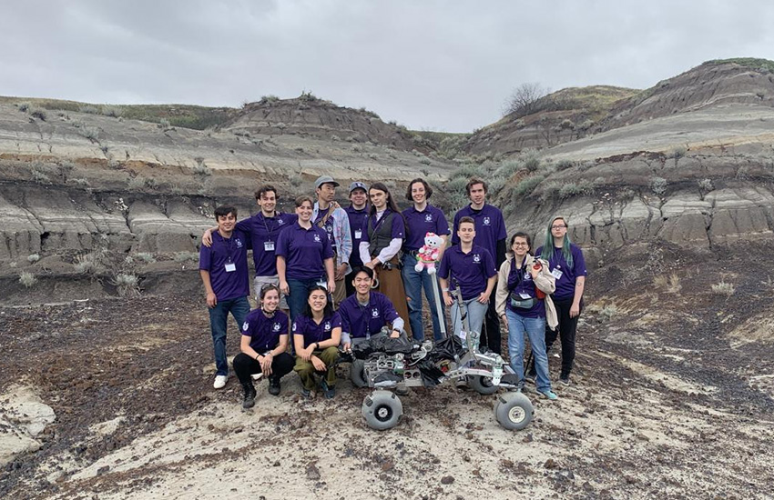 Members of the Husky Robotics team are pictured behind their robot.