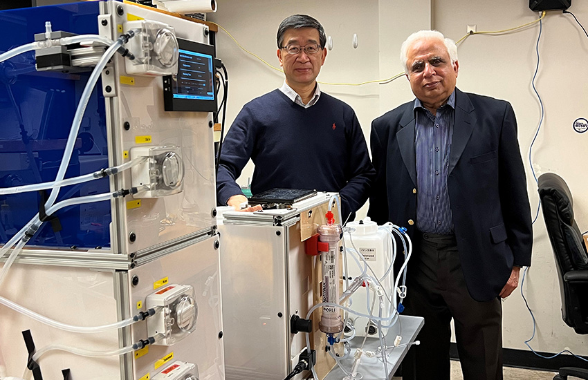 Dayong Gao and Suhail Ahmad stand next to each other in a lab. The AMOR machine is shown with its various tubes and pumps that remove toxins and pump fluids back into the bloodstream.