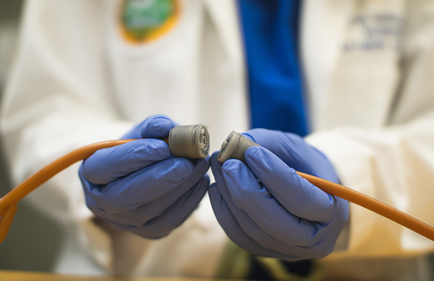 A person wearing a white doctor's coat holds tubing that is temporarily disconnected because of the device's breakaway mechanism.