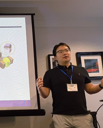 A man in a polo shirt stands next to a presentation.