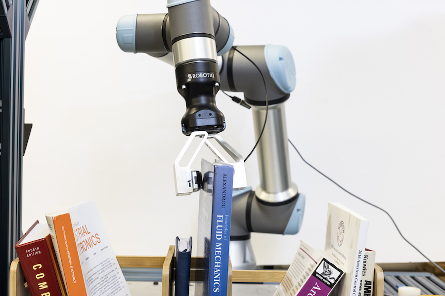 Robotic grasper grasping a book out of a shelf of objects.