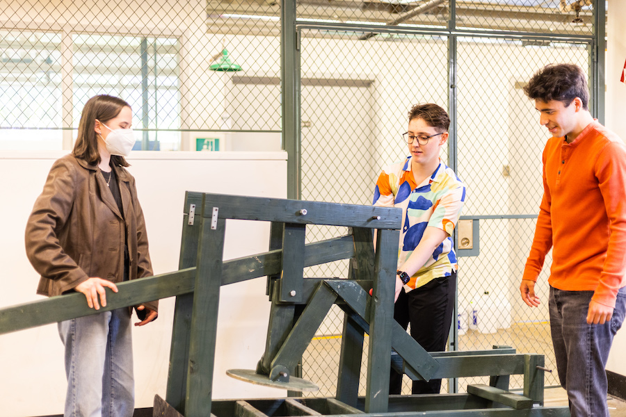 Three students interacting with a mechanical press