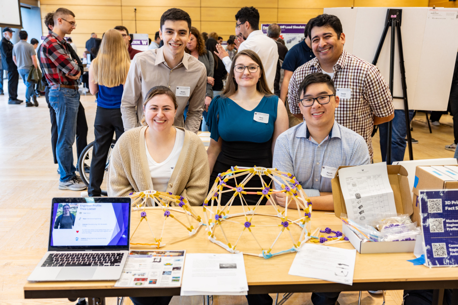 Five students are behind a table that holds domes that are part of a science activity for youth.