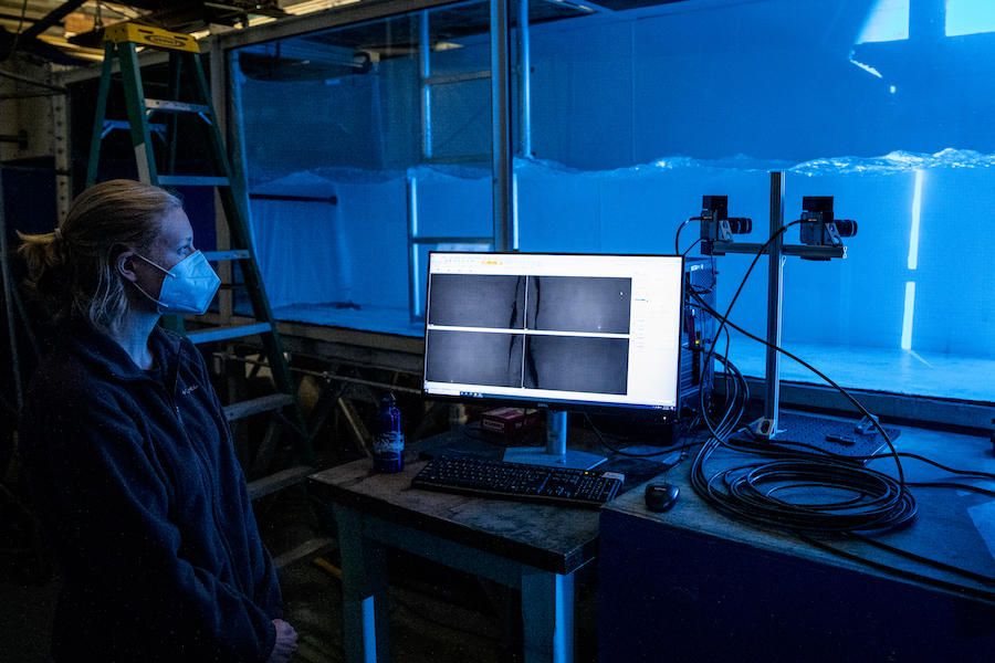 Female researcher at a water tank lab, looking at data on a computer