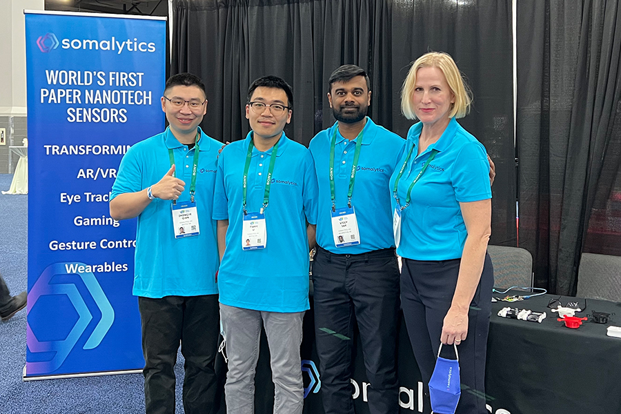 Group photo of four people at a conference booth