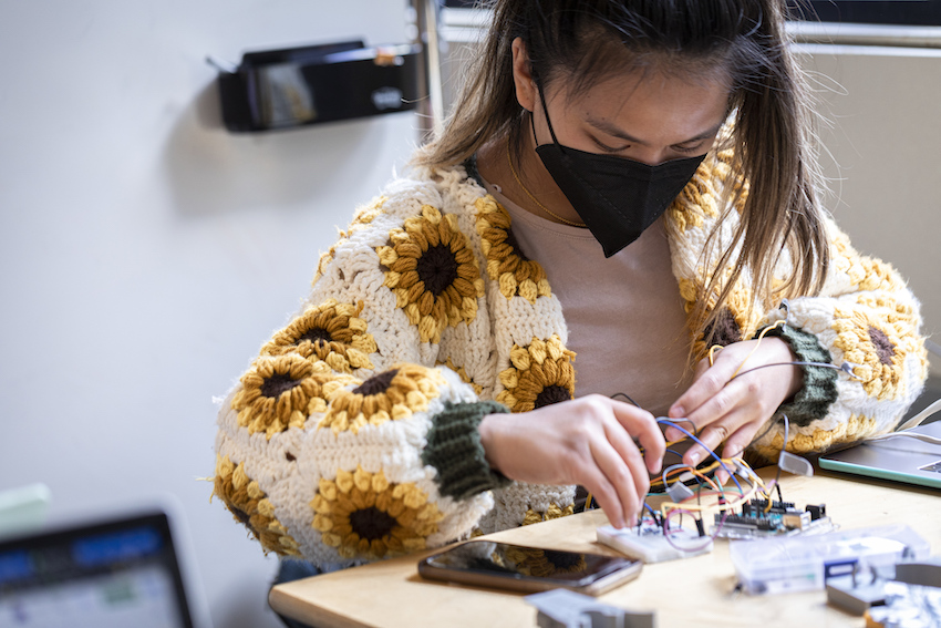 a person wearing a face mask working on a device