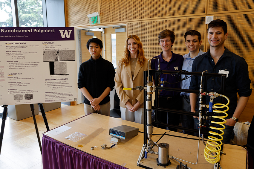 Five individuals stand in front of a presentation poster at a science exhibition.
