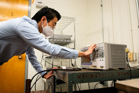 A researcher pressing buttons on an electronic device in a lab
