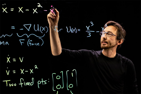 Professor Steve Brunton writing math equations on a lightboard with a marker