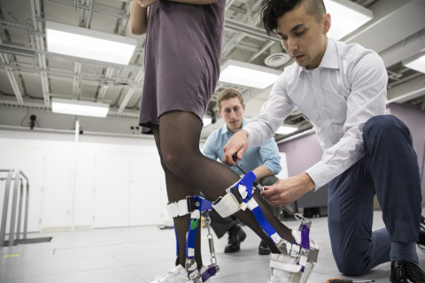 Two individuals working on fitting a prosthetic leg brace on a person in a clinical setting